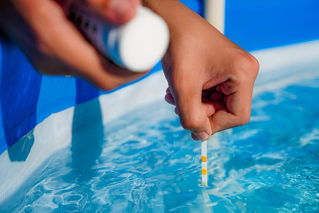 A person holds a test strip in pool water